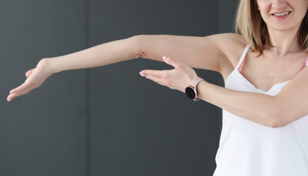 Young smiling woman showing her bent arm